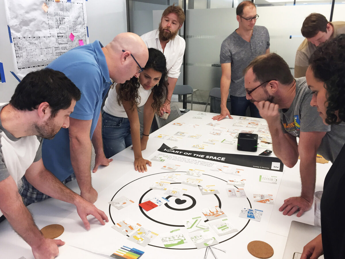 A team of engaged professionals collaboratively working around a circular diagram during a design thinking workshop.